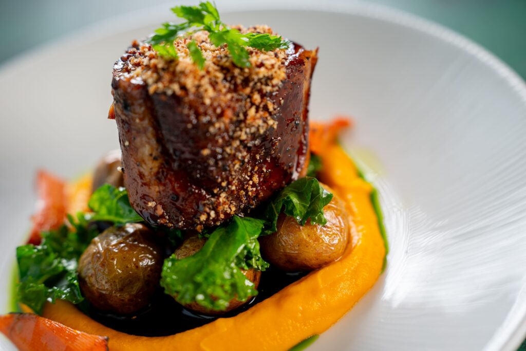 Moderní gastronomie v Praze může vypadat třeba takto: konfitovaný vepřový krk s baby bramborami, mrkvovým pyré, kadeřávkem a slaninovou strouhankou